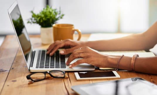 A woman types on her laptop as she sits at her desk. Email marketing is an important tool for business promotion.