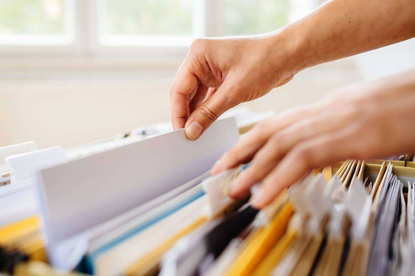 A person sorts through file folders and retrieves a needed document.