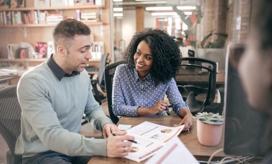 A couple sitting down at a table, filing their taxes for the first time.