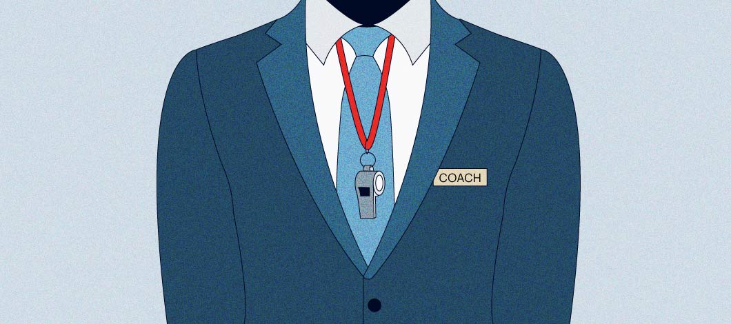 Trunk of a person wearing a blue suit and tie with a name tag that says “Coach” and a whistle around the neck.