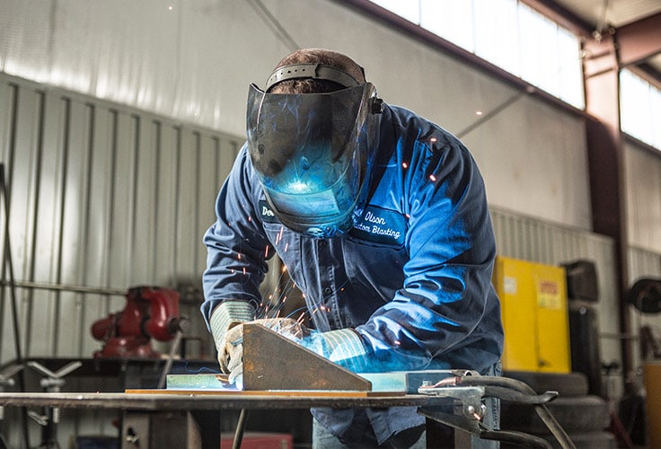 Welder with helmet on, working on material 