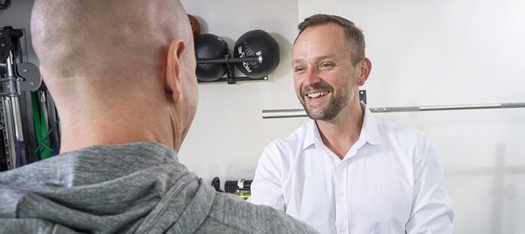 Chad Woodward speaks to a man at Symbio Physiotherapy. Merchant cash advances helped Woodward grow his business.