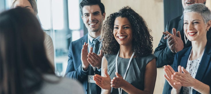 A group of businesspeople applaud for a co-worker.