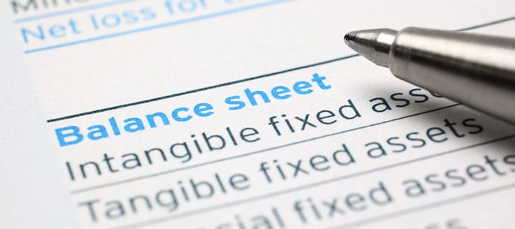 A pen rests on a paper that reads “balance sheet,” and lists intangible fixed assets as well as tangible fixed assets.