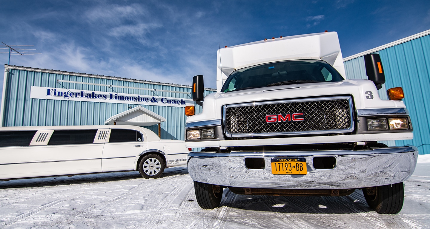 Photo of white GMC shuttle van and a white limousine in front of Finger Lake Limo's office.