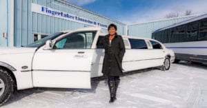 Owner of Finger Lakes Limousine, Tricia Sutliffe, stands in front of a white stretch limo with the door open