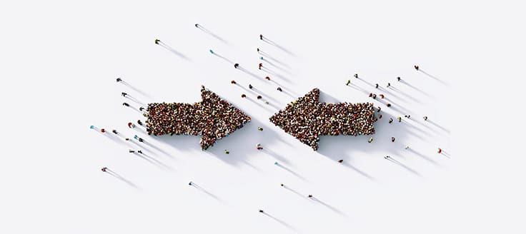 A crowd of people form two arrows pointing at one another.