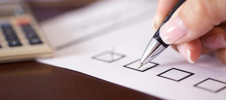 A person marks off boxes on a checklist, perhaps reviewing all the documents she needs for WBE certification.