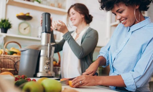 Young women slicing fruit at an eco-friendly smoothie bar business.