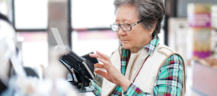 Woman paying at cashier register with a credit card. 