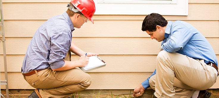 Two men conduct a home inspection. If you’re looking for an affordable franchise, some home inspection firms could be a good choice.