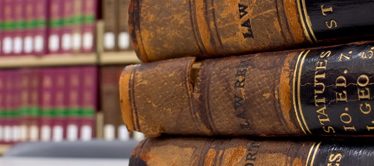 Books with battered spines are in a vertical stack in a law library.