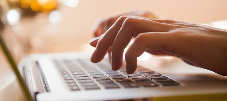 A person types on a laptop’s keyboard.