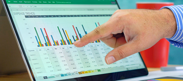 A businessman points to bar graphs on display on a tablet. He might be using a free accounting software program to generate reports for his small business.