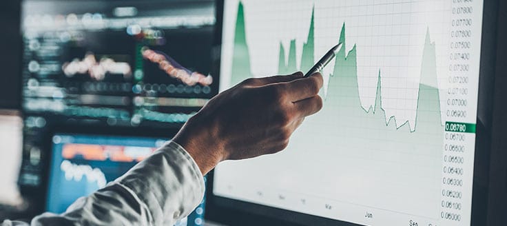 A man uses a pen to point to a peak on a chart. Purchase order financing can help you through a dip in cash flow.