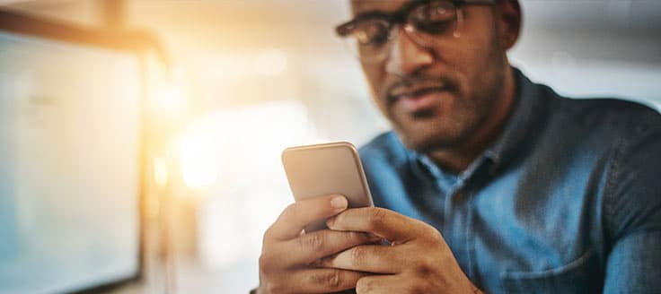 A man works on his smartphone, perhaps reviewing the finance app he uses to help manage his small business.