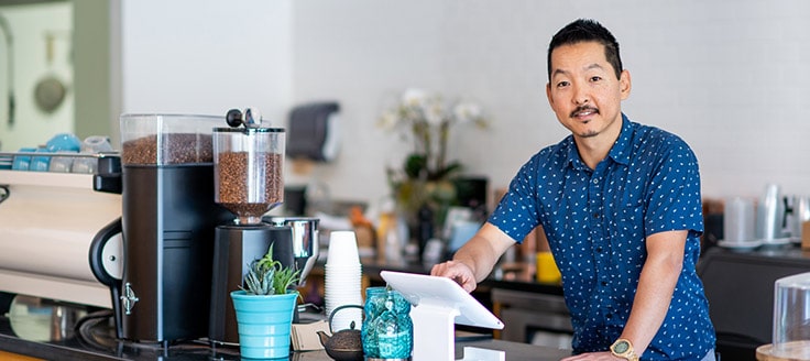 A coffee shop owner works with his payment service provider’s hardware to accept credit card payments from customers.