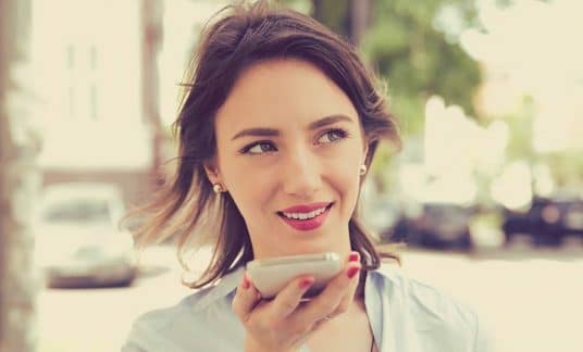 Woman using Google Voice while walking on a city street. 