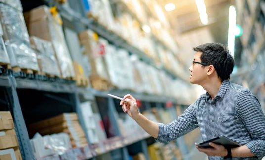 As part of his company’s inventory management system, a worker performs a physical check of inventory to verify stock levels.