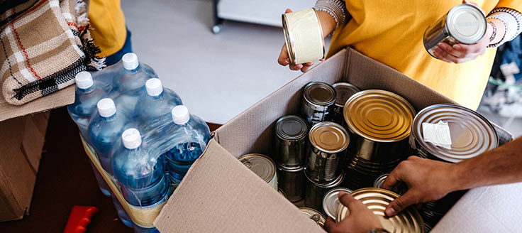 Workers place cans of food in a box for distribution. Giving back to the community was their business New Year’s resolution.