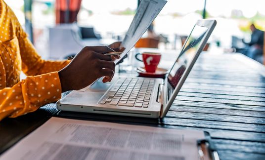 Person seated at a desk using a laptop computer.