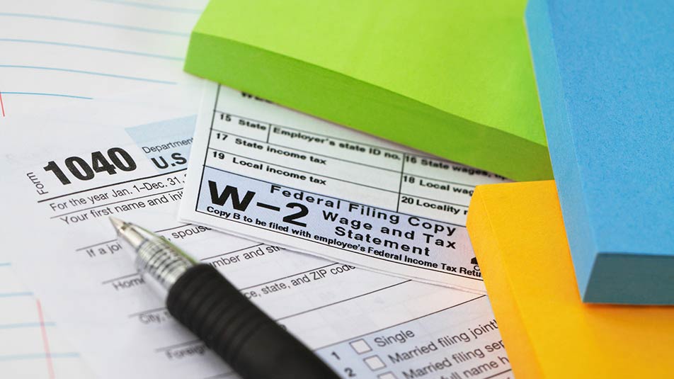 Form 1040, Form W-2, a pen and different color Post-It notes are spread out on a table