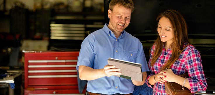 A man at a garage shows a woman an account of the completed work. Transparency is a good method to handle an angry customer.