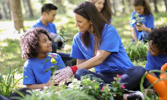 Woman giving a plant to a child