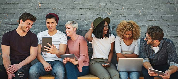 People sit on a bench and check out the web, possibly their favorite subreddits, on tablets and a laptop.