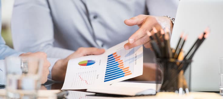 Businessmen review charts, which could show the change in prices for the raw materials their company purchases.