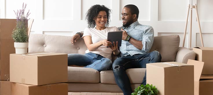 A couple sits down after moving into a new space. Reimbursing employees' moving costs is a taxable fringe benefit.