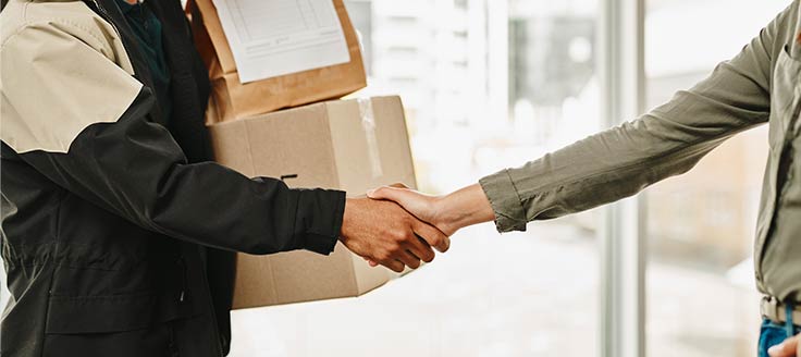 A delivery person and customer shake hands. A sincere thanks for a customer's business is a tip to handle an angry customer.