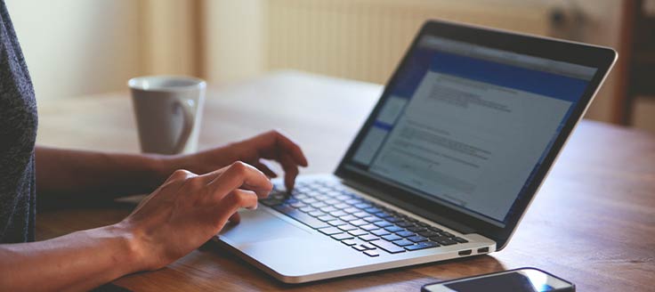 A woman works on a text document on her laptop. Microsoft Office alternative packages offer their own word processing apps.