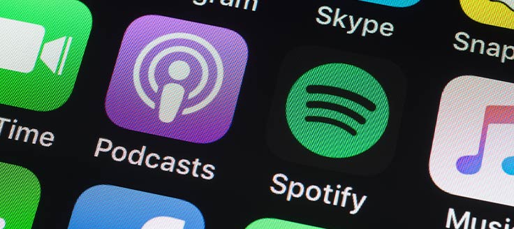 Apple Podcasts and Spotify icons on a smartphone screen. You can stream some of the best business podcasts with those apps.