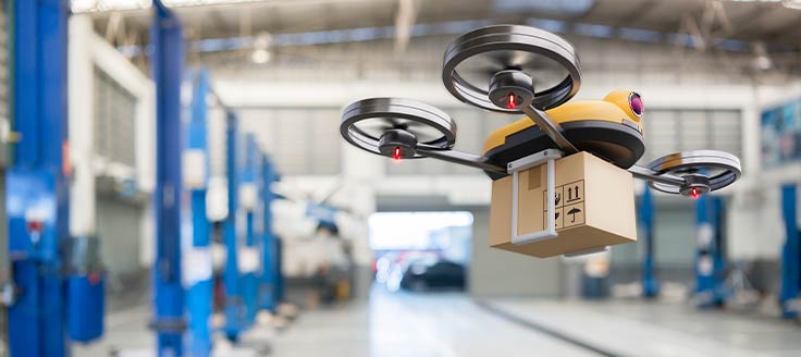 A drone flies a package through a warehouse to take the package to its next destination.