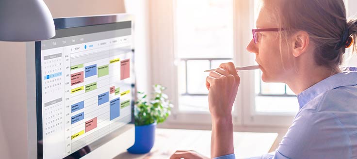 A woman views an online calendar on her computer screen. When working remotely due to coronavirus, use apps to stay on track.