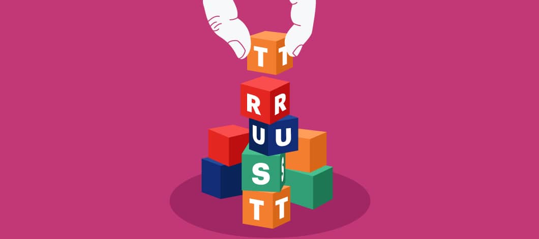 Building blocks form the word “Trust” with a hand adding the final block.