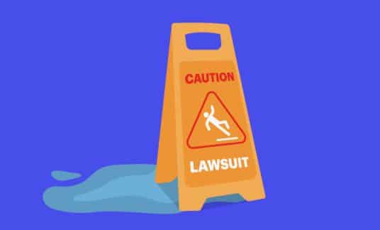 Blue background with a graphic of a caution sign placed over a puddle. The sign has the word “lawsuit” on it and an image of a person slipping.