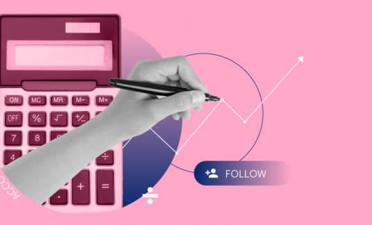 A hand holding a pen draws a financial graph next to a calculator.