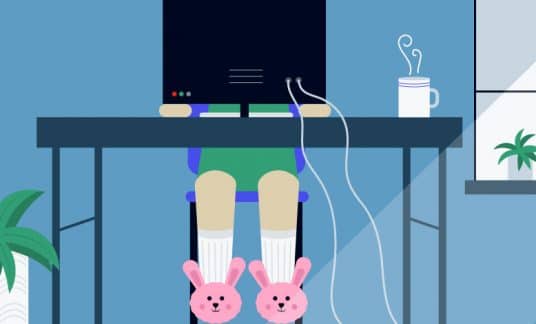 An employee working remotely from home sits at her desk. She’s wearing bunny slippers.