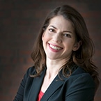 A smiling Jill Goldenziel amid a dark background