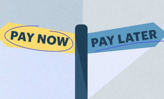 One sign reads “Pay Now” and points in one direction. The other sign, pointing in the opposite direction, reads “Pay Later.”