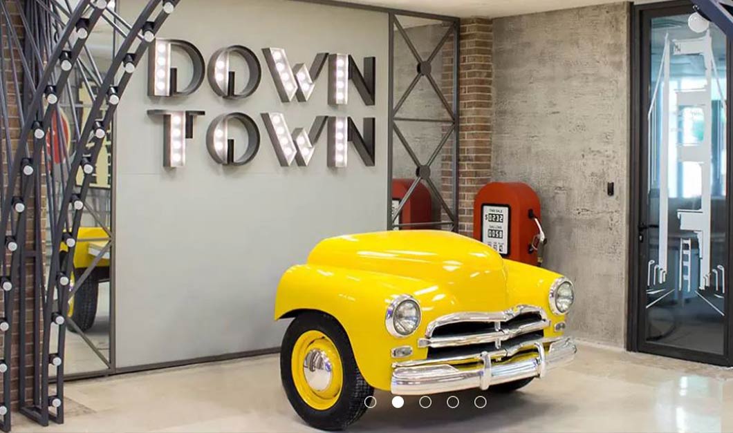 Photo of a creative installation with signage saying Downtown and the front portion of a yellow car