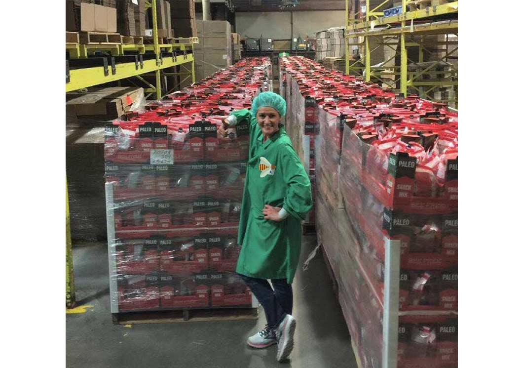 Image of a woman with protective clothing standing in front of a pallet of products at a production facility