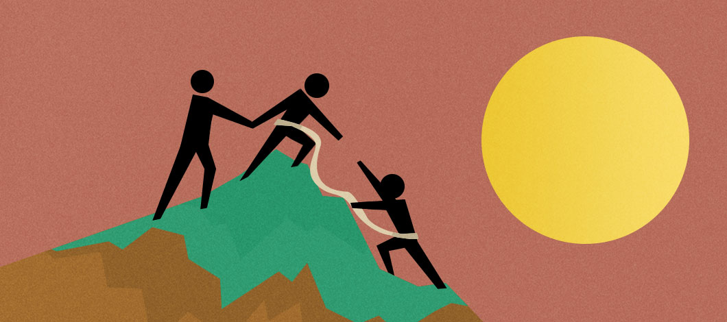 Two people at the top of a summit hold a rope and help pull up a new hire to join them.