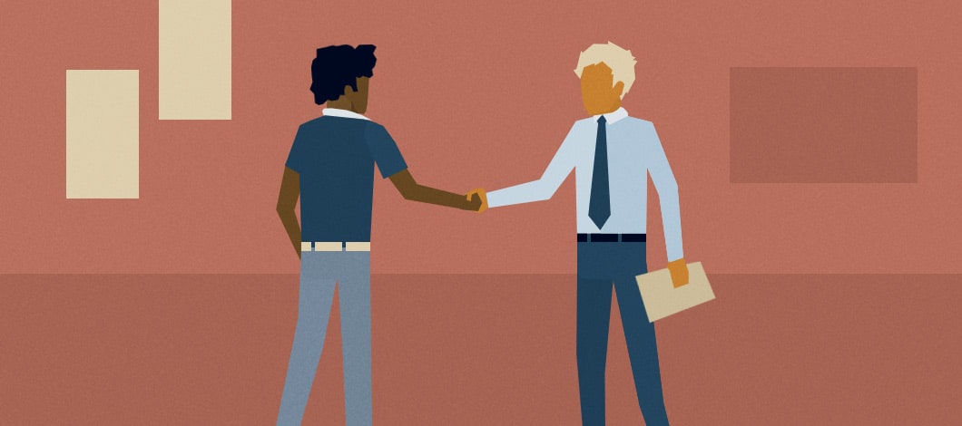 A new hire shakes hands with an employer in an office.