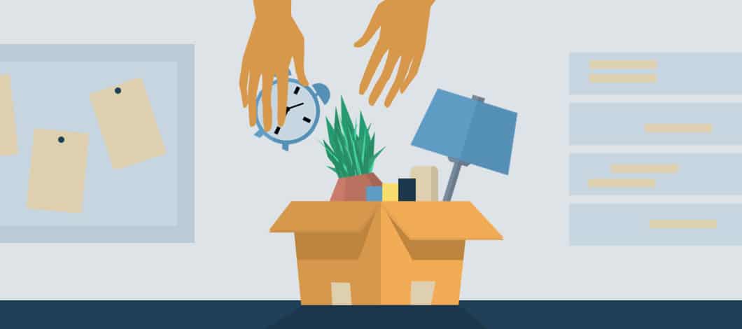 Hands pack personal items (including a plant, a lamp and a clock) into a box on a work desk.