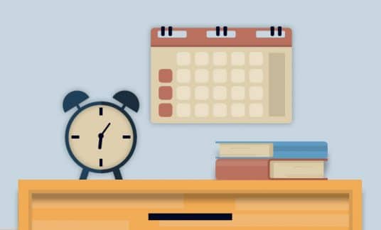 An alarm clock sits near a calendar hanging on a wall.