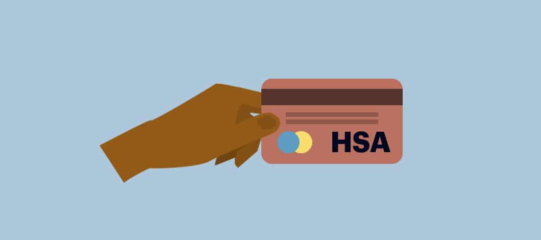 A hand holds up a credit card labeled, “HSA.”