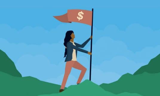 A woman plants a flag with a dollar sign at the summit of a mountain.